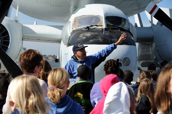 Volunteer and former naval aircrewman Hank Siefried talks to 5th graders about the E-1 Tracer early warning aircraft.