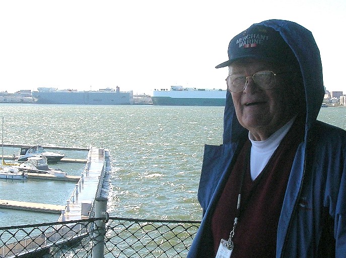 Volunteer Bob Barkus with a windy, choppy Charleston harbor in the background along with a few merchant ships at berth.