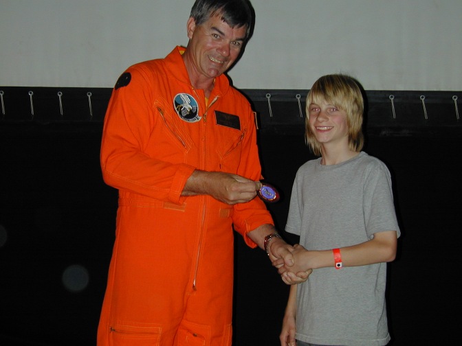 Scout Russell Wofford receives his Topgun patch from Commander Hills.