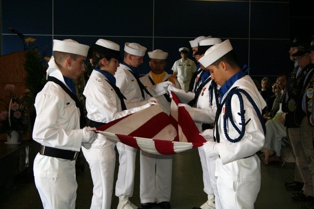 United States Navy color guard folds the colors for presentation to Mrs. Nuzum.