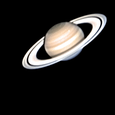 Saturn with storm seen as white spot on upper half.