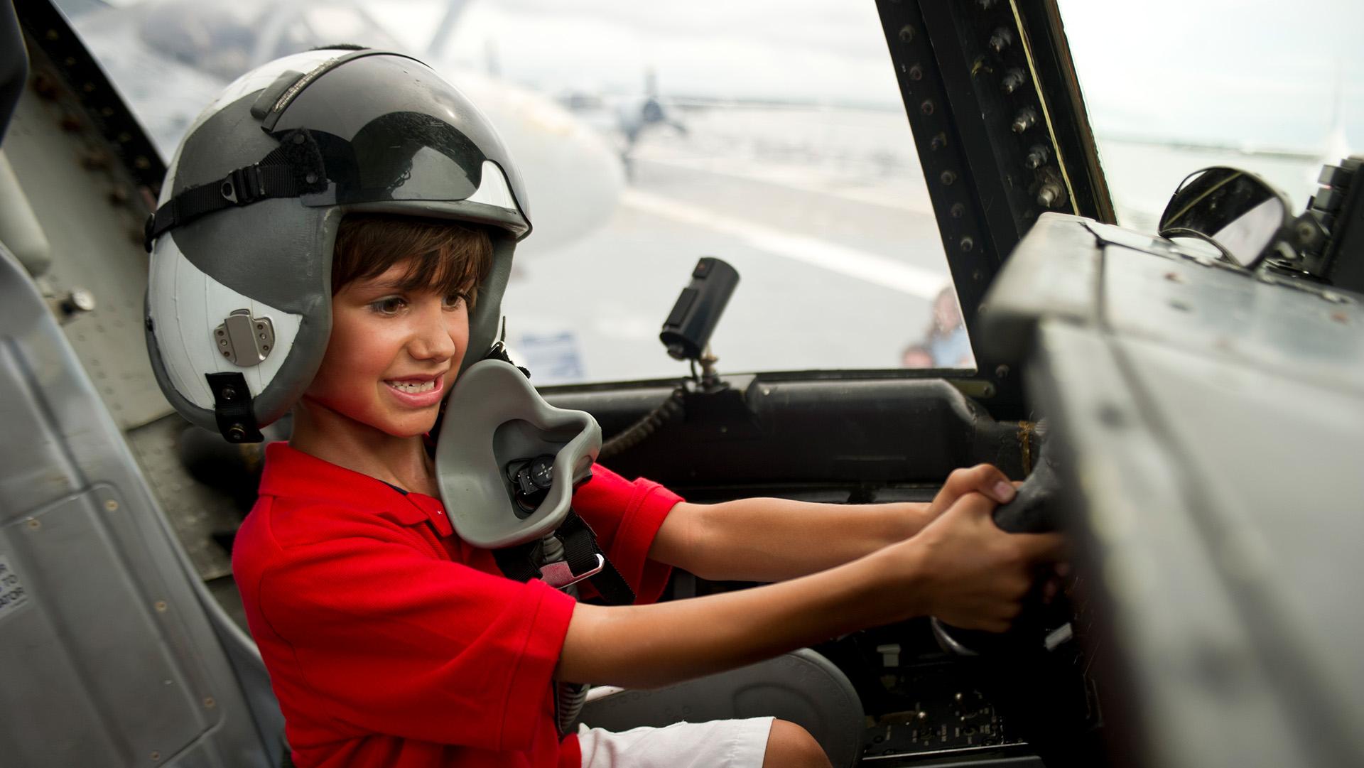 Young boy in a flight helmet at the controls of an aircraft