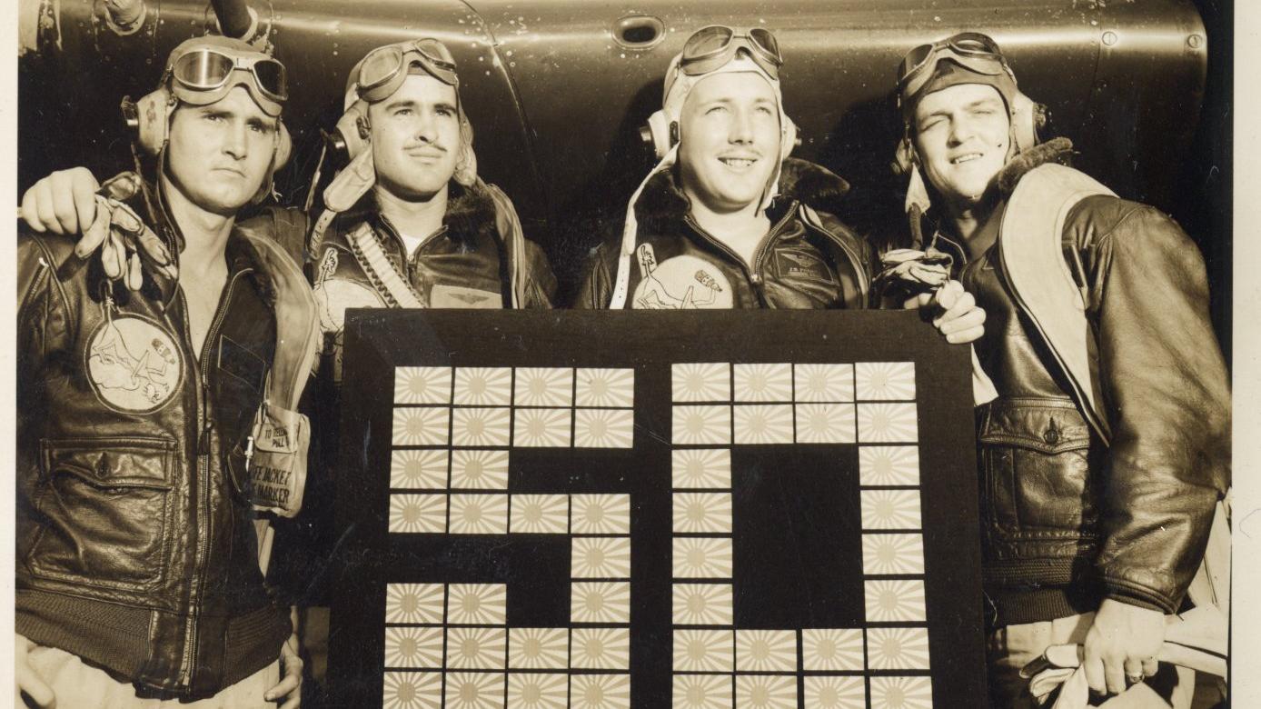 Vintage photo of four mean posing in front of an airplane.