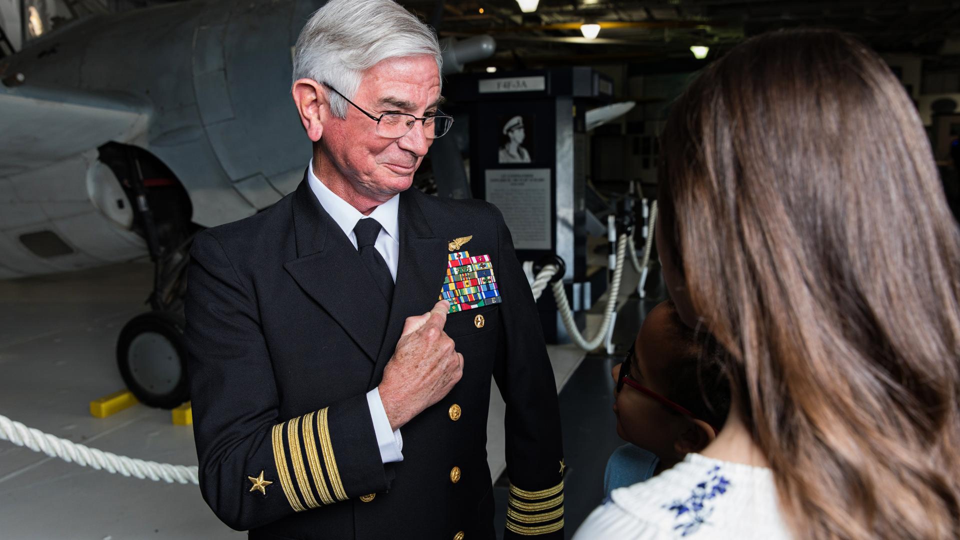 Guests interact with veteran in the hangar bay of the USS Yorktown