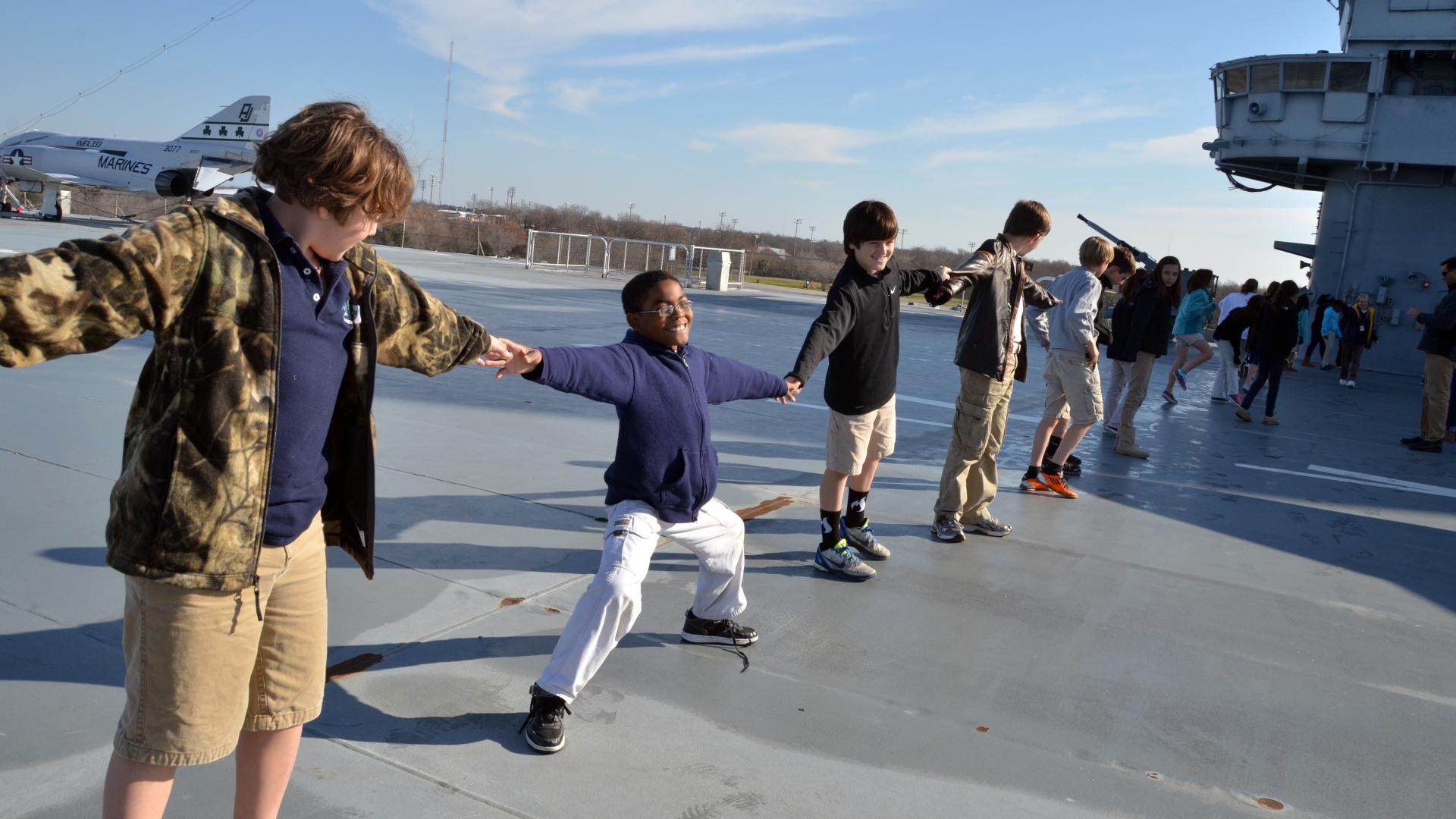 A group of students participate in an educational program on the flight deck of the USS Yorktown.