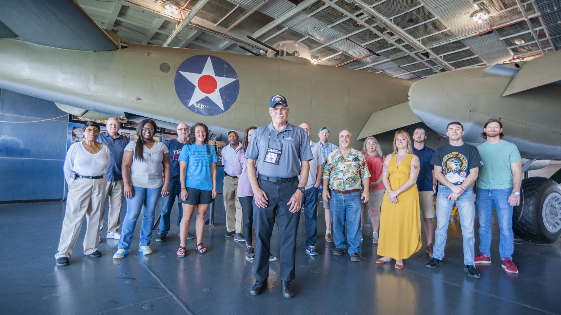 A tour group stands with their guide in front of aircraft at Patriots Point.