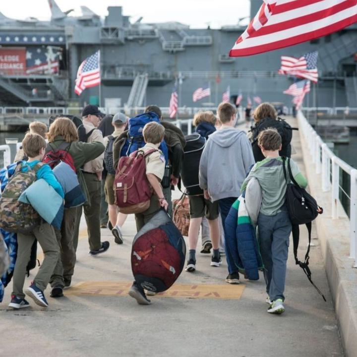 Kids and adults with overnight bags walking in