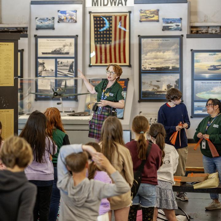 Patriots Point staff talk with campers in the hangar bay of the USS Yorktown.