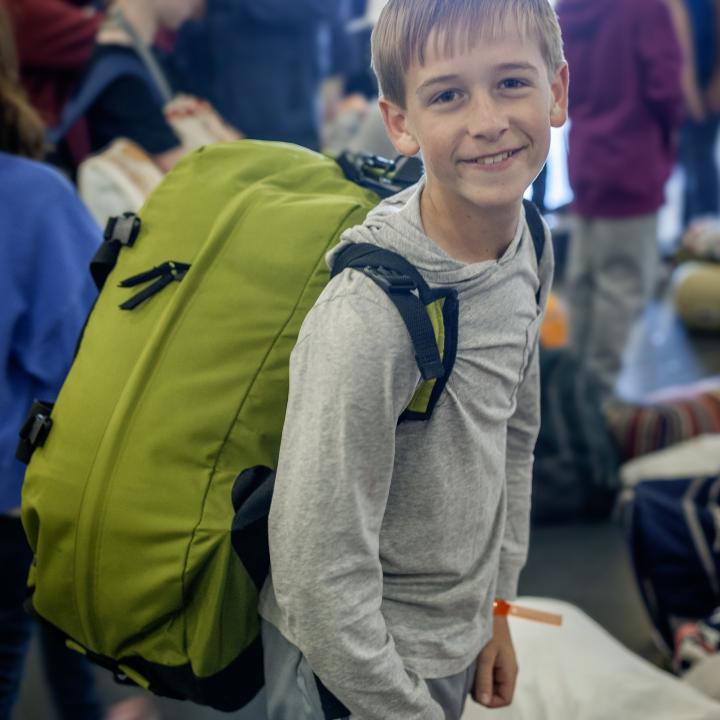 A boy smiles while holding a backpack during Operation Overnight.