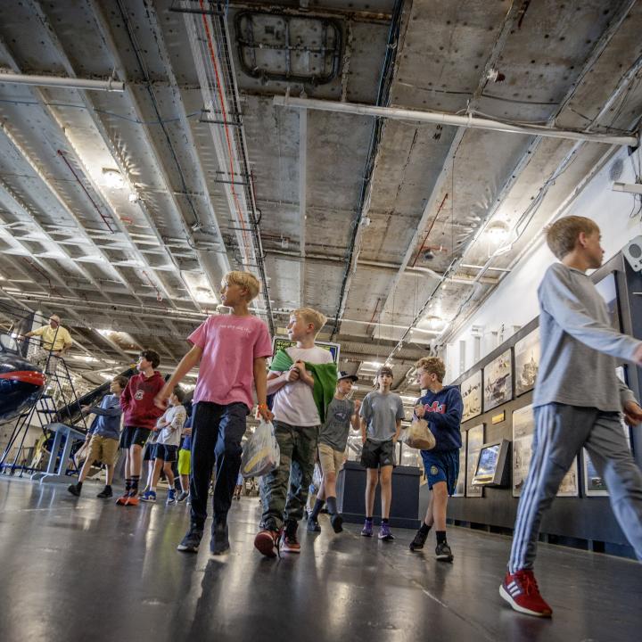 Kids walking the hangar bay on the USS Yorktown looking at the exhibits.