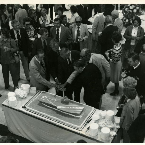 This photograph shows five men cutting a USS Yorktown-shaped cake for opening day ceremonies at Patriots Point, January 3, 1976.