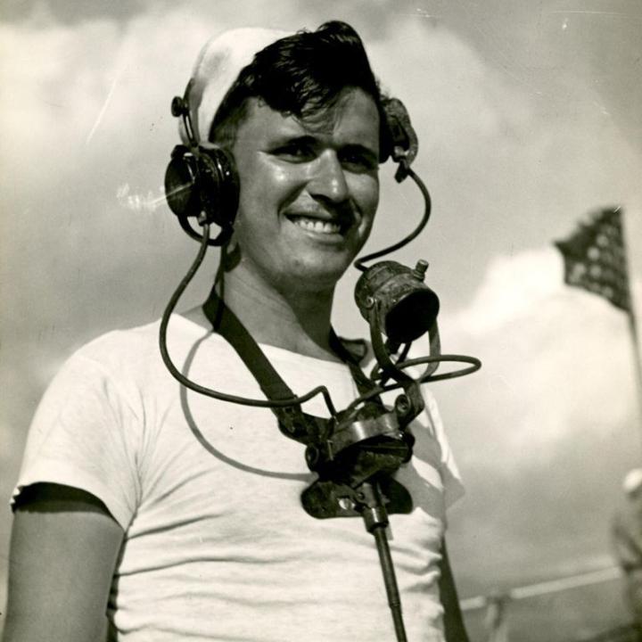 Thomas Fern, Seaman 1/c, standing outside wearing communication gear.