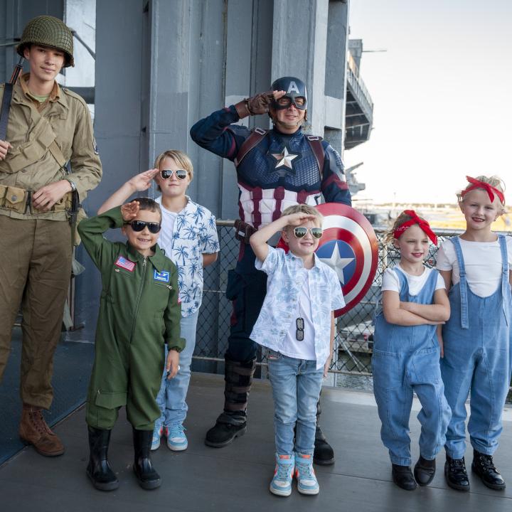 Group of guests and characters salute at Trick or Treat on the Yorktown