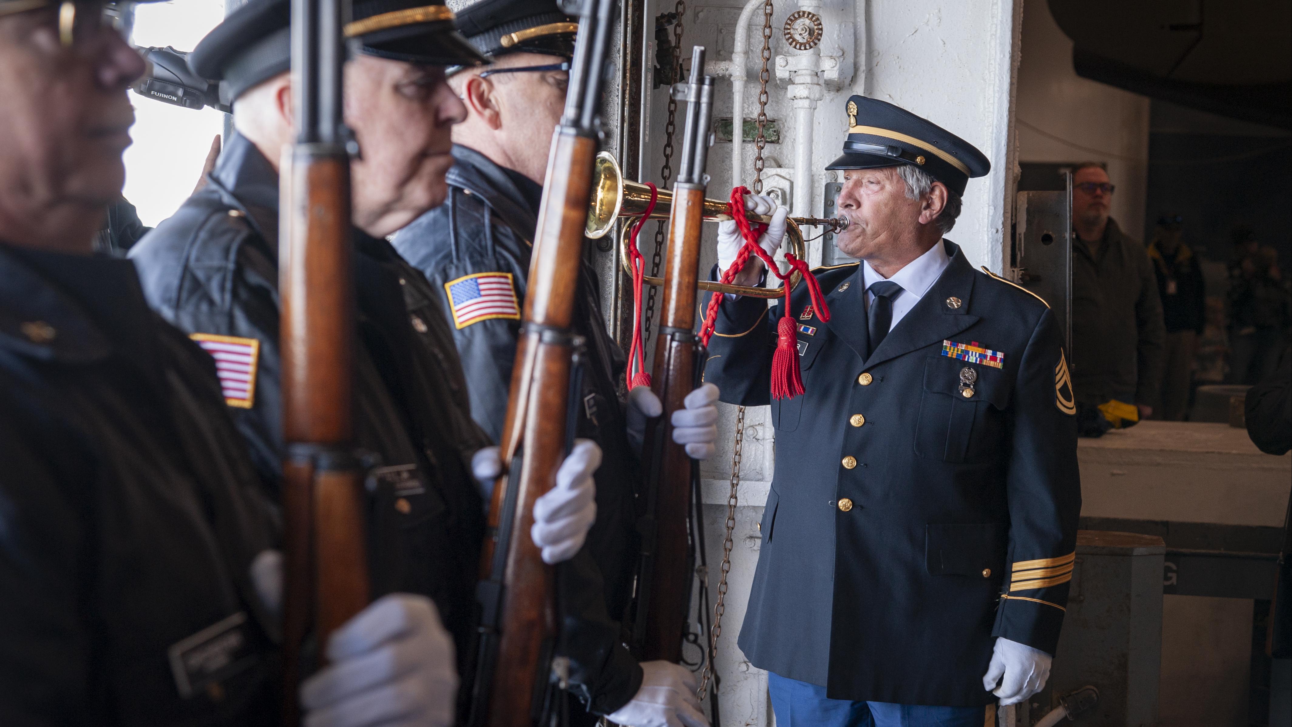 A solemn honor guard ceremony for National Pearl Harbor Remembrance Day aboard the USS Yorktown, with uniformed servicemen standing in formation holding rifles, while a bugler in military dress plays a ceremonial tune.