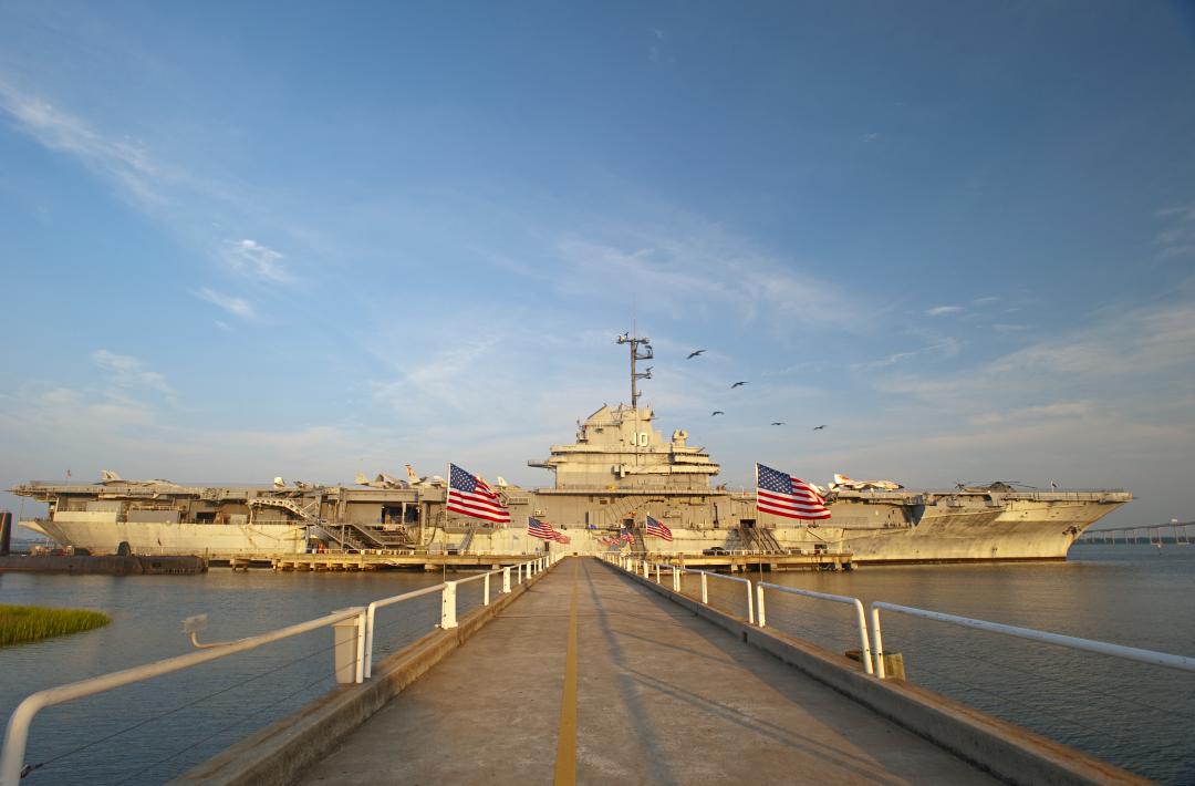 Walkway leading to the USS Yorktown aircraft carrier at Patriots Point, adorned with American flags on both sides.