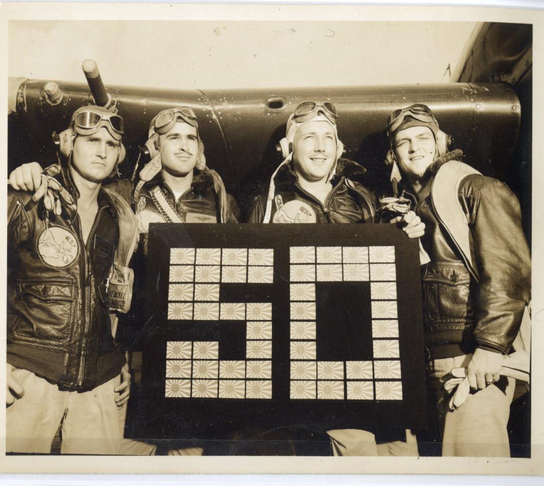Vintage photo of four mean posing in front of an airplane.