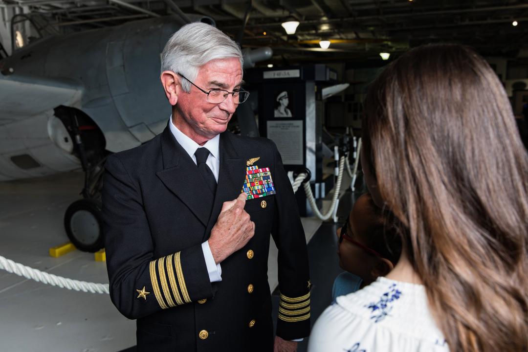 Guests interact with veteran in the hangar bay of the USS Yorktown