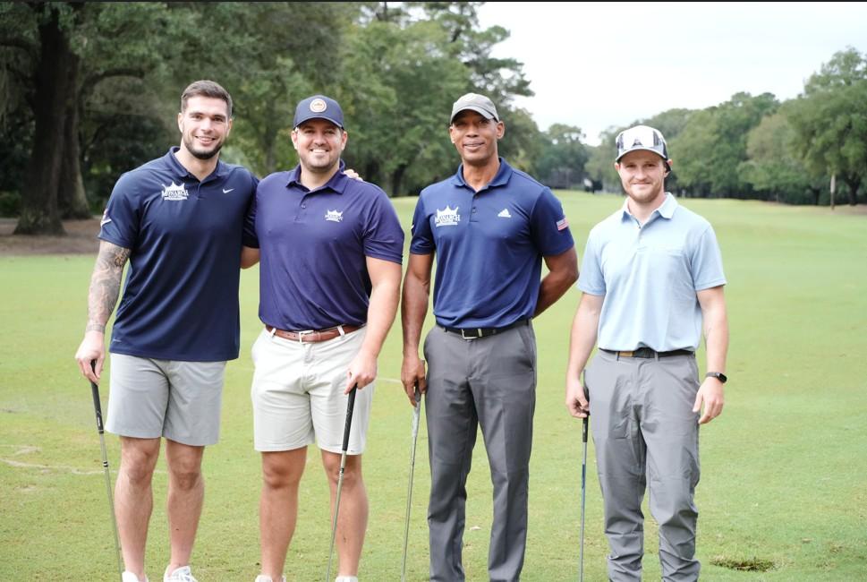 Four men pose for a picture on the golf course.