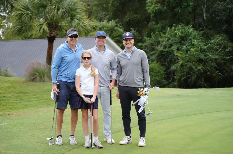 A family poses for a picture on the golf course.