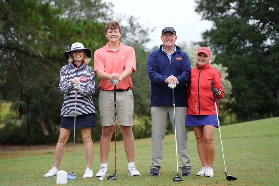 Four people pose for a picture on the golf course.