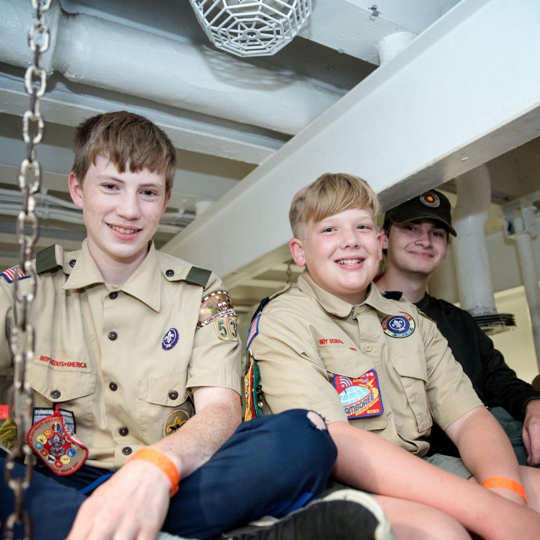 A group of scouts smile for a photo while sitting on the bunks at Operation Overnight.