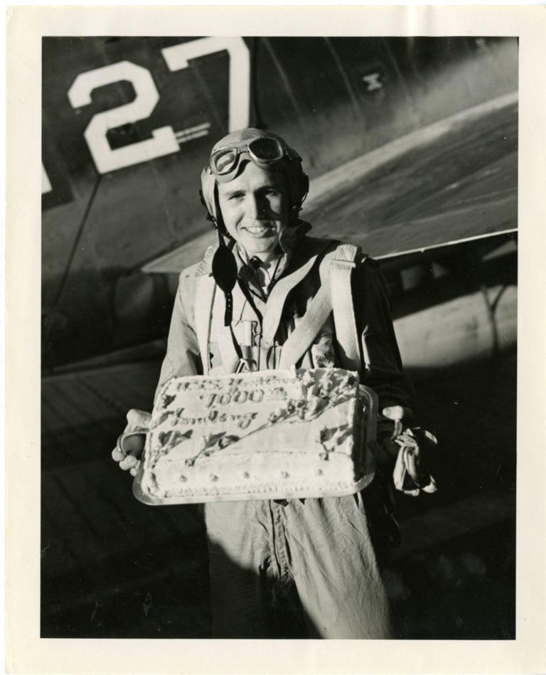 Smokey Stover holds up a cake celebrating the 7,000th landing on the USS Yorktown (CV-10)
