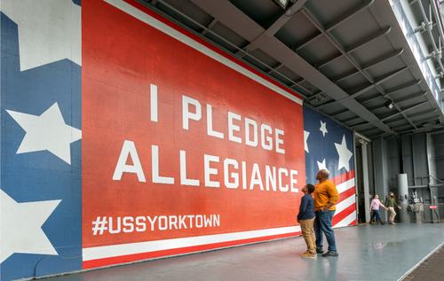Father and son look at the Pledge of Allegiance graphic near the entrance to the USS Yorktown.