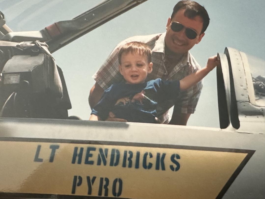 Man and child sitting in cockpit of aircraft. 