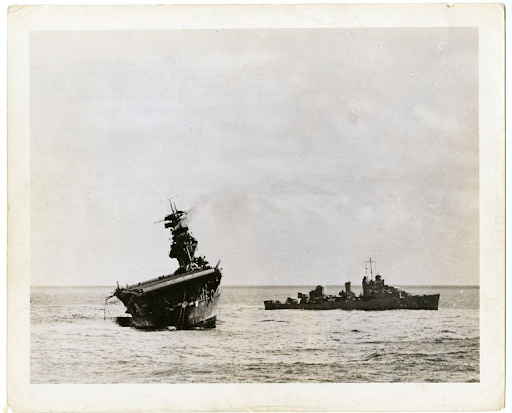 Official US Navy Photograph of the USS Yorktown (CV-5) listing heavily to port after sustaining damage at the Battle of Midway. The photo is dated September 16, 1942.